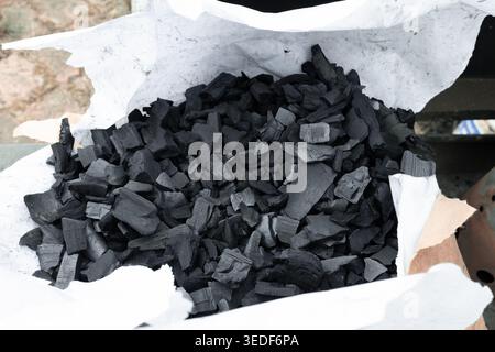Natural wood charcoal chunks in a white paper bag for BBQ. Stock Photo