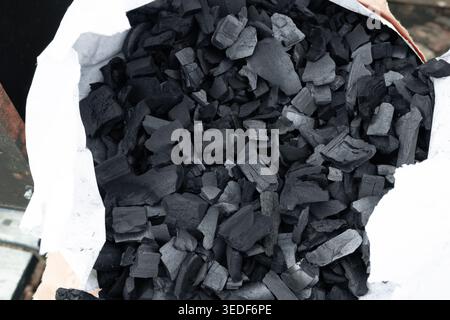 Natural wood charcoal chunks in a white paper bag for BBQ. Stock Photo