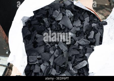 Natural wood charcoal chunks in a white paper bag for BBQ. Stock Photo