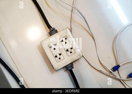 An old electrical outlet with multiple exposed wires showcases the importance of safety and maintenance in home and industrial environments. Stock Photo