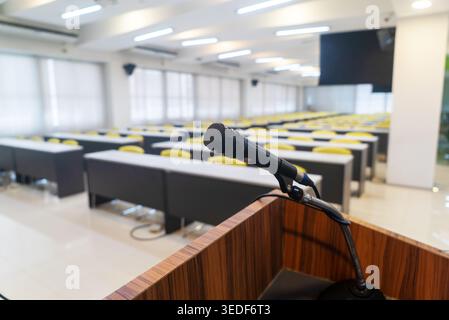 A modern conference room featuring an empty space with bright lighting and a microphone, ideal for corporate meetings and presentations. Stock Photo
