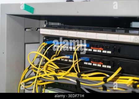 Close-up of a server rack displaying organized fiber optic cables in vibrant yellow and blue. Ideal for tech, network, and data communication concepts Stock Photo