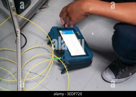 A technician is seen using a network testing device to analyze cabling and connections. The image captures a close-up view of technology in action. Stock Photo