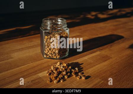 Glass jar of bee bread with granules spilled on a table. Natural beekeeping product, rich in vitamins, organic superfood and healthy nutrition concept Stock Photo