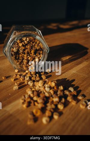 Glass jar of bee bread with granules spilled on a table. Natural beekeeping product, rich in vitamins, organic superfood and healthy nutrition concept Stock Photo