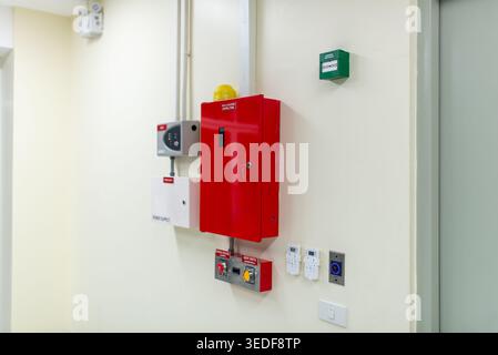 This image features fire safety equipment installed on the wall of a modern building, showcasing a red control panel and related devices for emergency Stock Photo