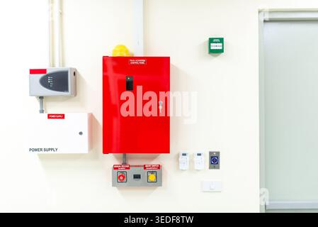 A vibrant red fire alarm panel mounted on a clean white wall, showcasing safety equipment and technology for emergency notifications and responses. Stock Photo