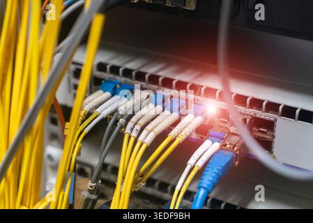 Close-up view of fiber optic cables connected to a network hub, showcasing vibrant colors and a glowing connection in a modern data infrastructure set Stock Photo