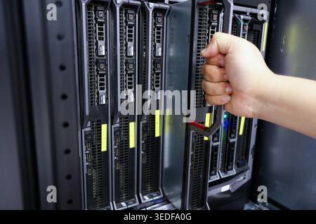 A technician performing maintenance on a server rack, showcasing advanced hardware in a data center environment with attention to detail and technolog Stock Photo