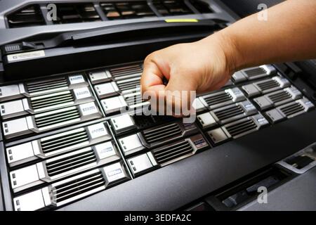 A close-up view of a hand striking a server in a data center, highlighting the power and force involved in managing technology and infrastructure. Stock Photo