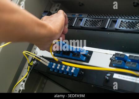 A skilled network technician connects cables in a server rack, showcasing essential hardware installation and infrastructure management in an IT setti Stock Photo