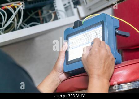 A technician is using a handheld device for data entry in a modern workspace. This image captures technology in action, emphasizing tools and workflow Stock Photo