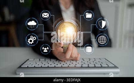 Business professional using technology for innovation and data management with glowing light bulb concept, demonstrating creativity and digital Stock Photo