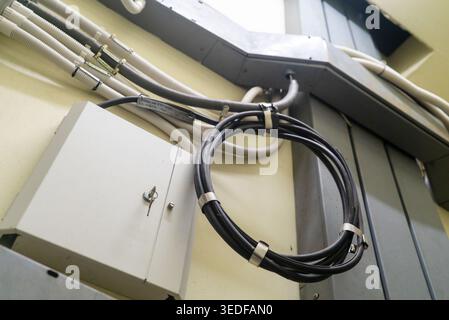 This image shows a wire management system featuring a looped cable secured to a wall-mounted junction cabinet, representing efficient organization and Stock Photo