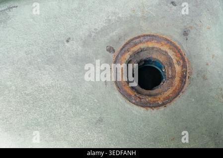 A close-up view of a rusty metal surface featuring a circular hole, showcasing the intricate details of corrosion and texture, perfect for industrial Stock Photo