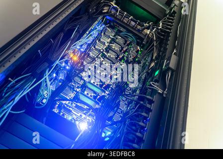 An interior view of a server rack showcasing multiple servers interconnected with various cables and illuminated lights, representing modern technolog Stock Photo