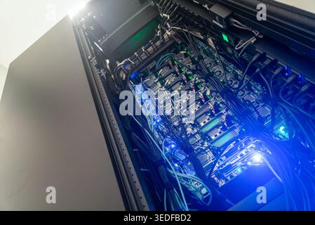 This image showcases a high-tech server rack filled with advanced computing equipment and illuminated by striking blue LED lights, highlighting modern Stock Photo