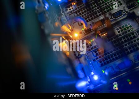 Captivating close-up view of illuminated server components, showcasing intricate details of hardware, circuits, and vibrant blue and orange lights in Stock Photo
