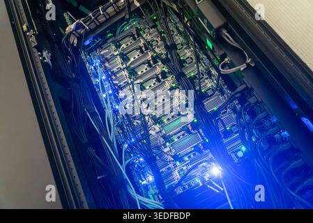 This image features a modern server rack showcasing advanced technology with neon blue lighting. The intricate wiring and hardware illustrate the core Stock Photo