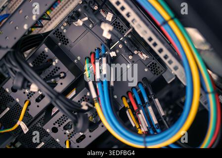 A closeup view of colorful cables in a server rack, showcasing the complexity of modern technology and infrastructure in data management systems. Stock Photo