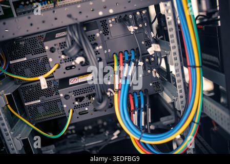 A close-up view of colorful network cables connecting devices in a computer server rack, showcasing advanced technology and efficient data management Stock Photo