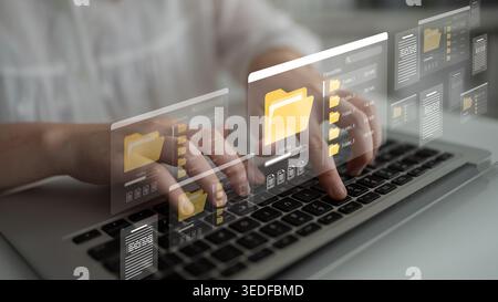 A person interacts with a laptop, showcasing an advanced digital file management interface featuring folder icons, symbolizing modern productivity and Stock Photo
