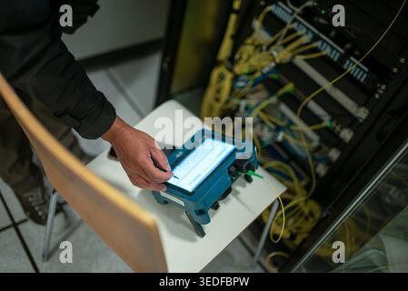 A technician uses specialized equipment to analyze network performance in a modern server environment, ensuring efficient connectivity and communicati Stock Photo