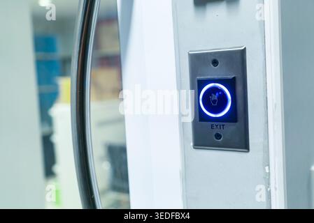 This image showcases a modern exit button featuring a bright blue illuminated indicator. Ideal for illustrating safety, accessibility, and contemporar Stock Photo