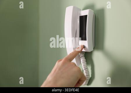 Man pressing button on intercom panel indoors, closeup Stock Photo