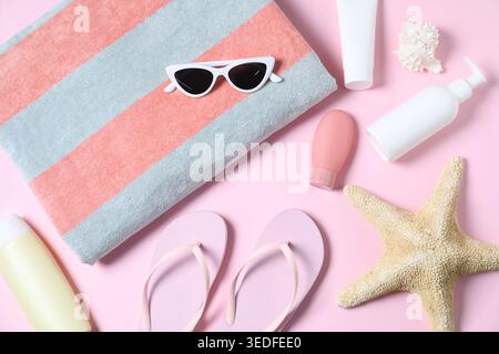 Flat lay composition with towel and other beach accessories on pink background Stock Photo