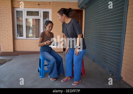 Engaging Conversation Between Two Women While Enjoying Beverages Outside in a Casual Setting Stock Photo