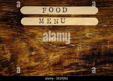 Close up FOOD MENU stamped sticks on weathered dark wood table. Top view, horizontal Stock Photo
