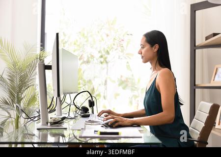Focused woman working remotely with two computer screens Stock Photo