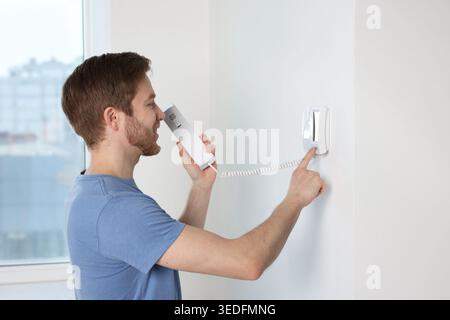 Man pressing button on intercom panel indoors Stock Photo