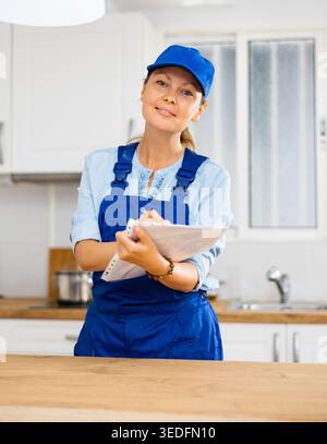Woman house cleaner making notes in kitchen Stock Photo