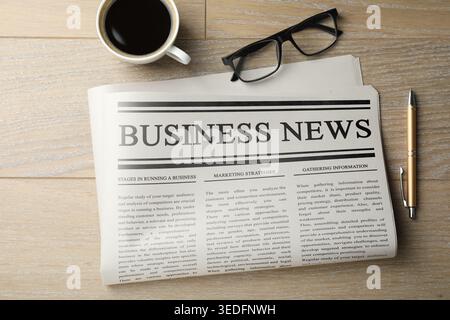 Newspaper, coffee, glasses and pen on wooden table, flat lay Stock Photo