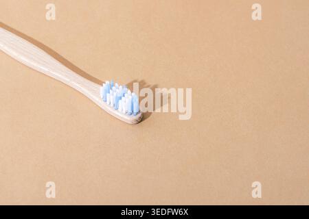 Bamboo toothbrush with white and blue bristle on beige background, eco friendly oral care concept. Top view, copy space. Stock Photo