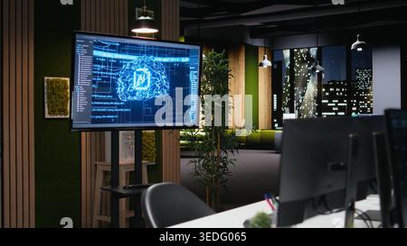 Artificial intelligence algorithms displayed on screen in modern high rise office late at night. Visualization of 3D neural network brain models on glowing monitor in empty workplace Stock Photo
