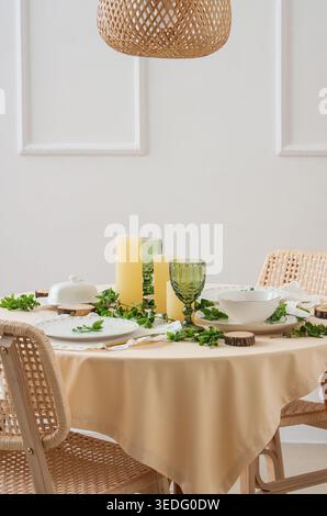 Beautiful table setting with plates, candles and green branches Stock Photo