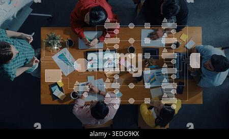 Collaborative Business Meeting with Charts and Diagrams on a Table Surrounded by Diverse Professionals Engaging in Strategy and Planning Activities Stock Photo