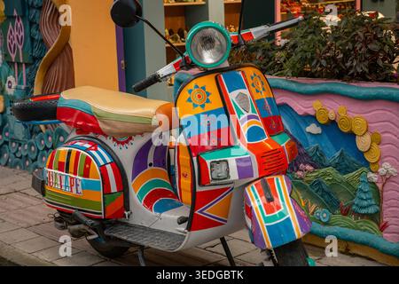 Guatape, colombia - enero 14, 2026 decorated scooter with vibrant flags and patterns parked on a cobblestone street, showcasing traditional zócalos in Stock Photo