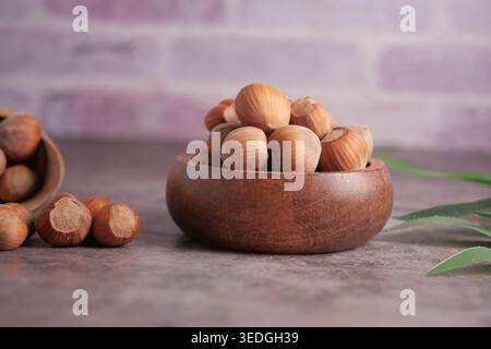 Hazelnuts in wooden bowl on table with blurred background Stock Photo