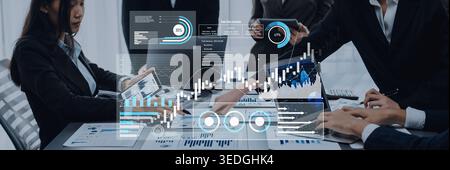 Professionals engage in a business meeting, analyzing digital data and financial graphs to strategize for future growth and success in a modern office Stock Photo