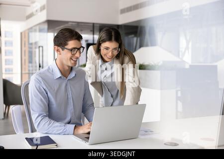 Two colleagues reviewing information on laptop in contemporary city office Stock Photo