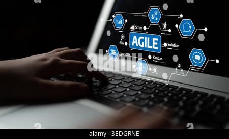 A close-up view of hands typing on a laptop keyboard, featuring a visual representation of agile methodology concepts like Scrum and Kanban Stock Photo