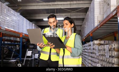 Latin warehouse workers working together using laptop Stock Photo