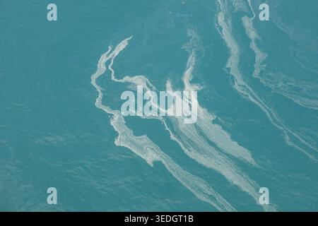 Sea foam creating abstract patterns on the surface of turquoise ocean water Stock Photo