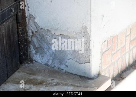 Damaged building wall texture with paint flaking off and plaster crumbling, needing renovation Stock Photo