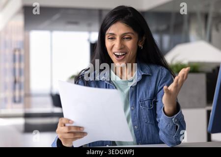 Indian woman reading unexpectedly great news in workplace Stock Photo