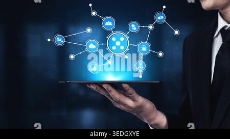 A businessman displays a tablet showcasing a vibrant digital network with icons representing technology and data. This image reflects innovation and Stock Photo